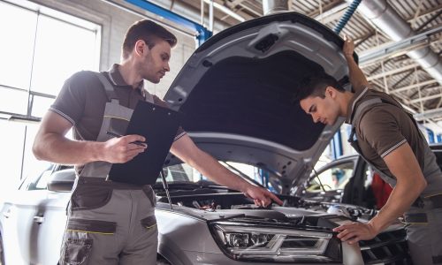 Handsome,Young,Auto,Mechanics,In,Uniform,Are,Examining,Car,While