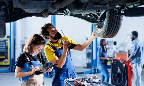 Technicians,Collaborating,On,Servicing,Broken,Vehicle,,Checking,For,Faulty,Wheels.